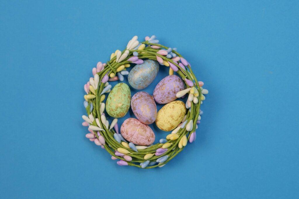 Colorful Easter eggs in a pastel wreath on a bright blue background. Perfect for festive decor.